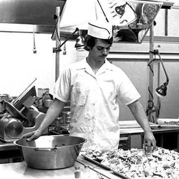 A culinary student works in a 赌钱app可以微信提现 kitchen classroom.